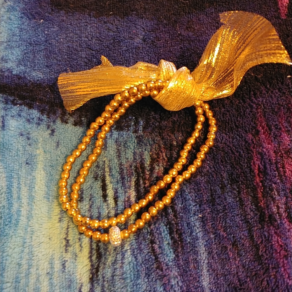 HP Golden bracelet with a small sparkly silver donut and a golden ribbon bow